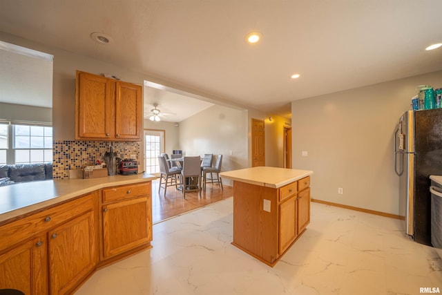 kitchen with marble finish floor, decorative backsplash, light countertops, and freestanding refrigerator