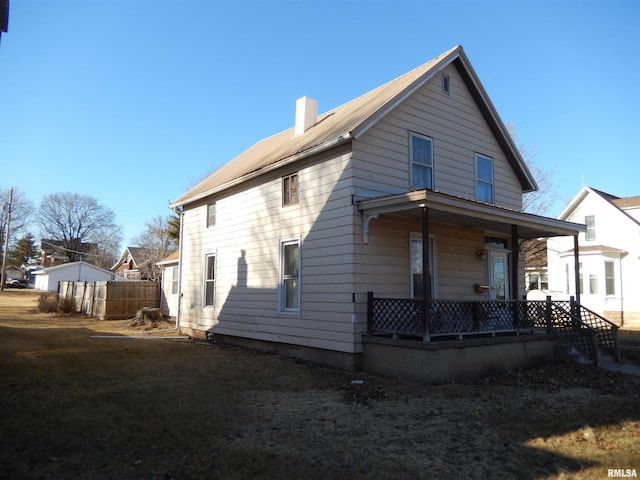 rear view of house featuring a chimney, fence, a porch, and a lawn