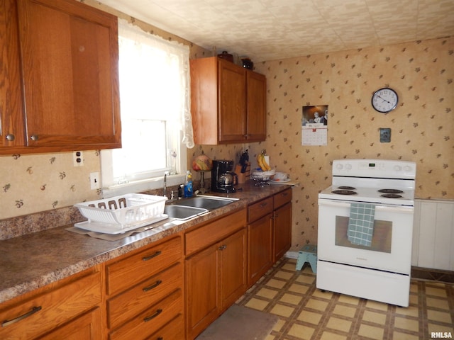 kitchen with brown cabinetry, wallpapered walls, light floors, and white range with electric cooktop