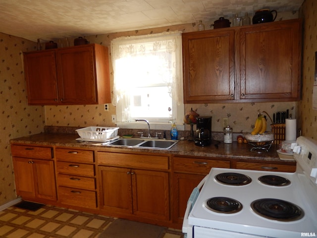 kitchen featuring white electric range, brown cabinetry, a sink, and wallpapered walls