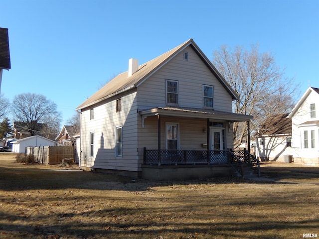 view of front of home featuring covered porch, a chimney, a front yard, and fence