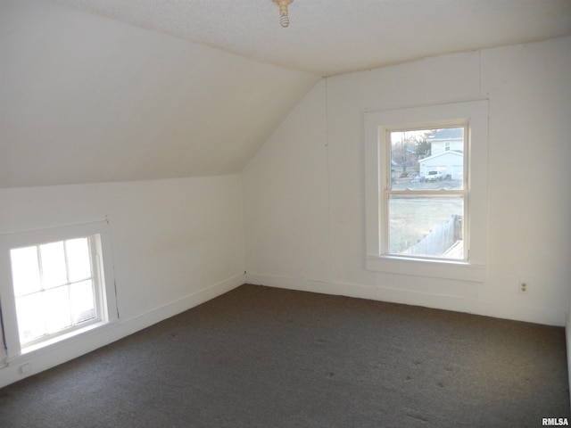 additional living space with lofted ceiling, dark carpet, and a wealth of natural light