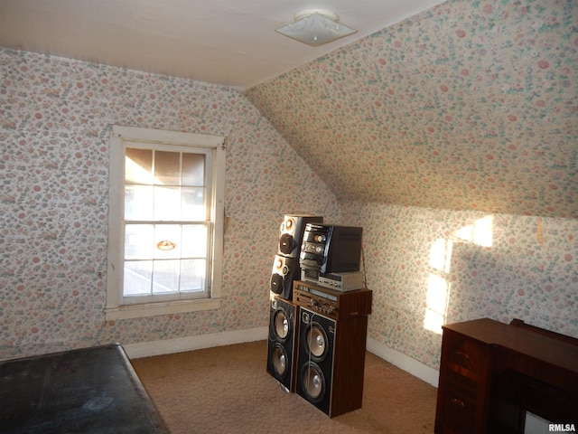 interior space featuring lofted ceiling, baseboards, carpet flooring, and wallpapered walls