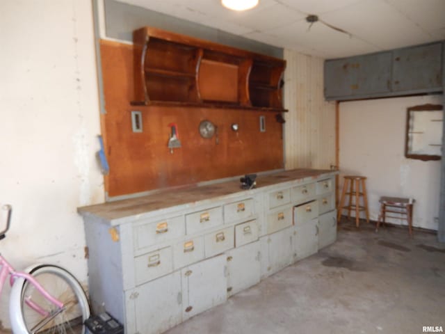 kitchen featuring open shelves and unfinished concrete flooring