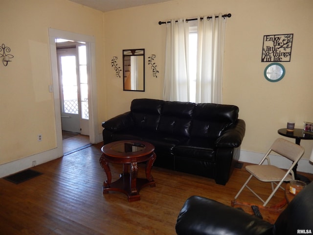 living room with visible vents, baseboards, and wood finished floors