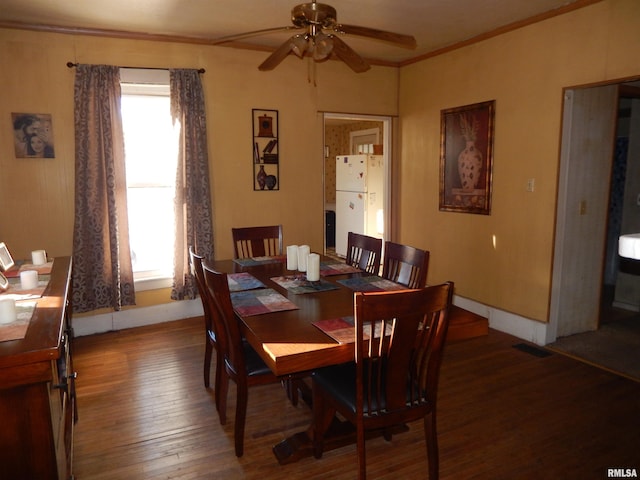 dining room featuring ornamental molding, a healthy amount of sunlight, baseboards, and hardwood / wood-style flooring