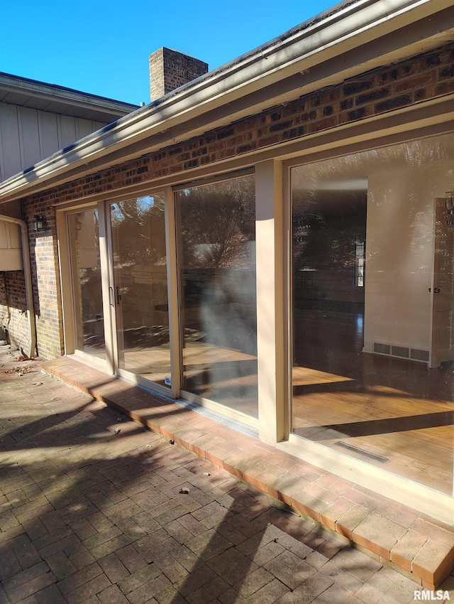 property entrance featuring board and batten siding, brick siding, and a chimney