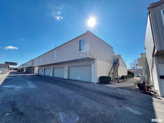 view of side of property with stairway, community garages, and central air condition unit