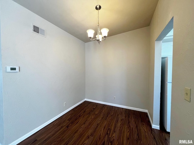 empty room with dark wood-style floors, visible vents, baseboards, and a chandelier