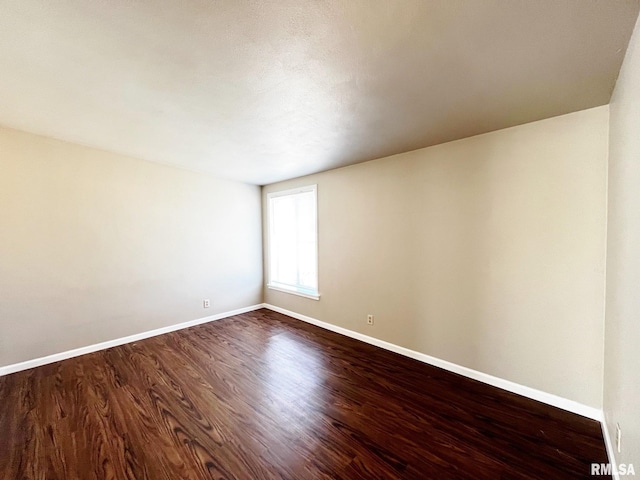 empty room featuring baseboards and dark wood finished floors