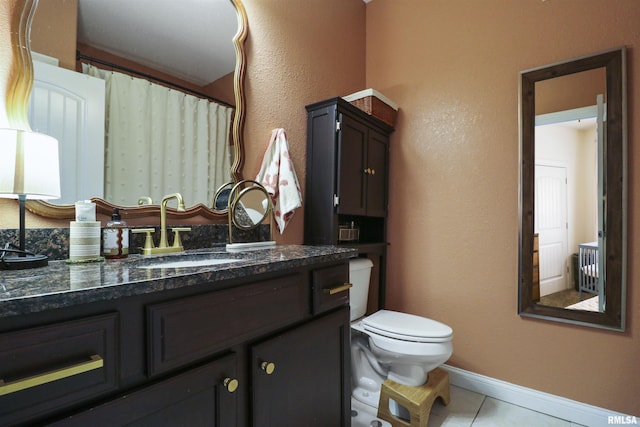 bathroom with tile patterned flooring, baseboards, vanity, and toilet