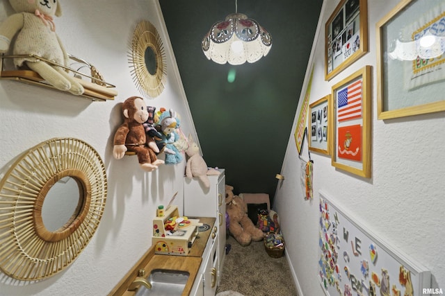 interior space with a textured wall, carpet flooring, a sink, and baseboards