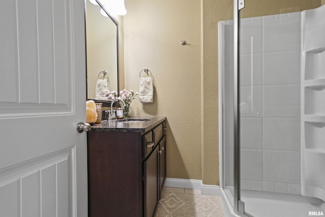 full bath with a stall shower, vanity, baseboards, and tile patterned floors