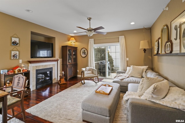 living room featuring baseboards, a ceiling fan, a tile fireplace, dark wood-style floors, and recessed lighting