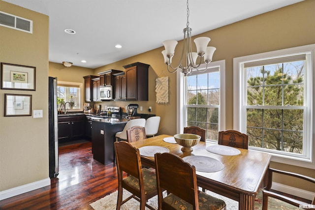 dining space featuring dark wood-style floors, baseboards, visible vents, and a chandelier