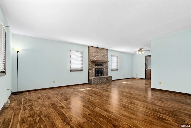 unfurnished living room featuring a ceiling fan, a fireplace, baseboards, and wood finished floors