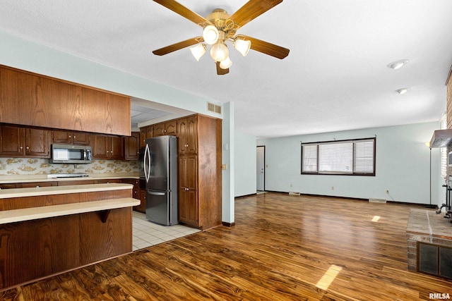 kitchen with light wood-style flooring, appliances with stainless steel finishes, open floor plan, and light countertops