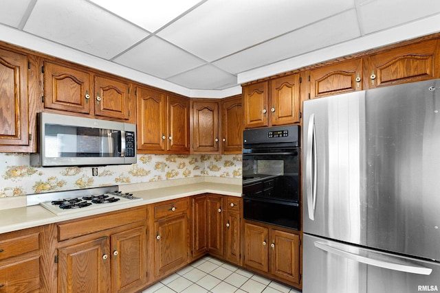 kitchen with appliances with stainless steel finishes, brown cabinetry, and wallpapered walls