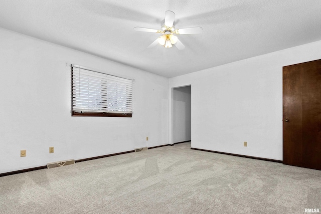 empty room with a ceiling fan, a textured ceiling, visible vents, and carpet flooring