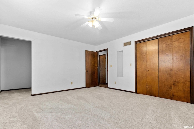 unfurnished bedroom with carpet, a closet, visible vents, and ceiling fan