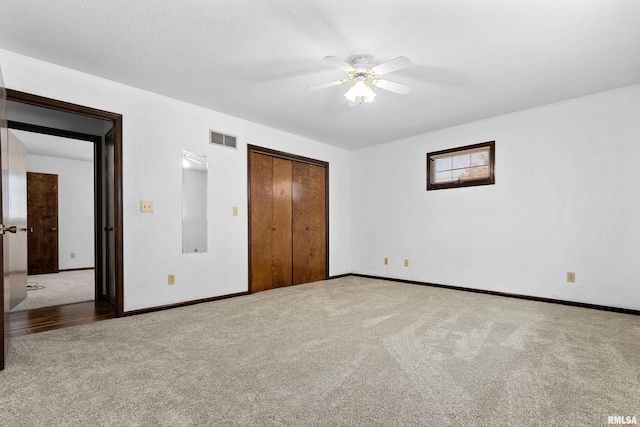 unfurnished bedroom featuring carpet, a closet, visible vents, a ceiling fan, and baseboards