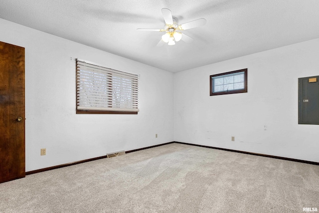 unfurnished room featuring a textured ceiling, carpet floors, visible vents, a ceiling fan, and electric panel