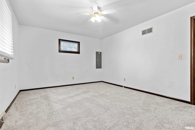 carpeted spare room featuring visible vents, ceiling fan, electric panel, and baseboards