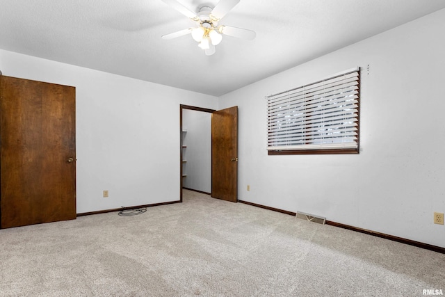 unfurnished bedroom with baseboards, visible vents, ceiling fan, and carpet flooring