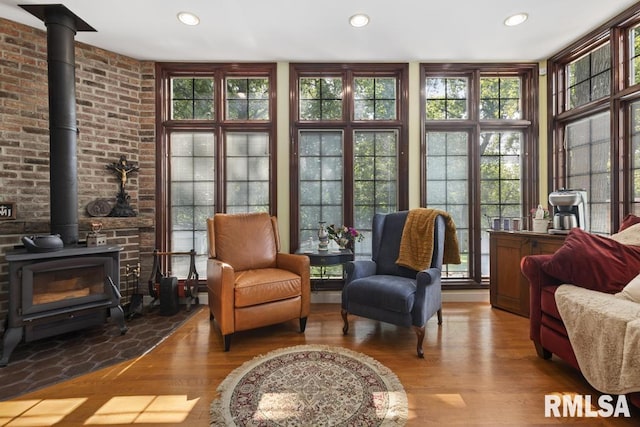 sitting room with a wood stove, wood finished floors, and recessed lighting