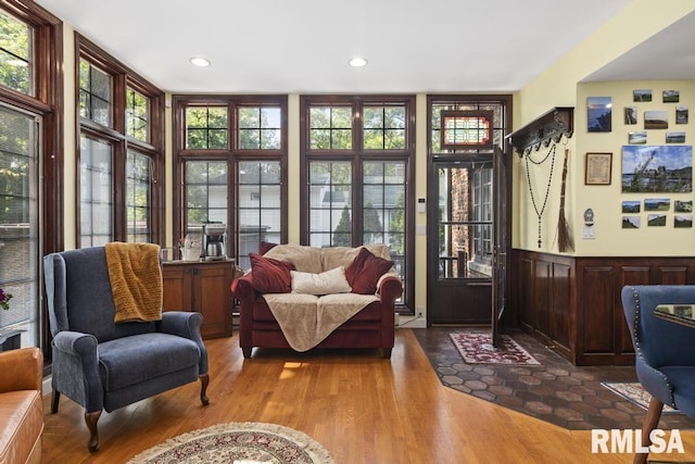 living area with recessed lighting, a wainscoted wall, and wood finished floors