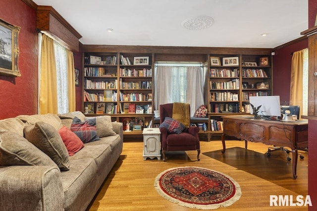 sitting room with built in features, crown molding, and wood finished floors