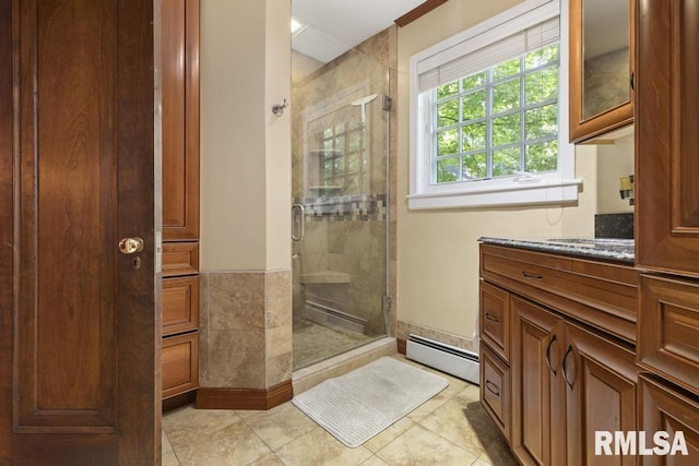 bathroom featuring a baseboard heating unit, tile patterned flooring, a shower stall, and vanity