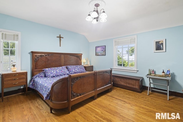 bedroom featuring multiple windows, a notable chandelier, baseboards, and wood finished floors