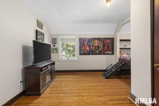 interior space featuring lofted ceiling, light wood-style flooring, and baseboards