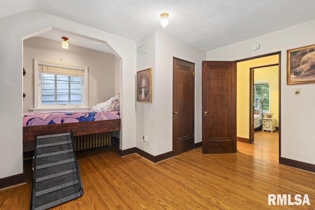 bedroom featuring baseboards, visible vents, and wood finished floors