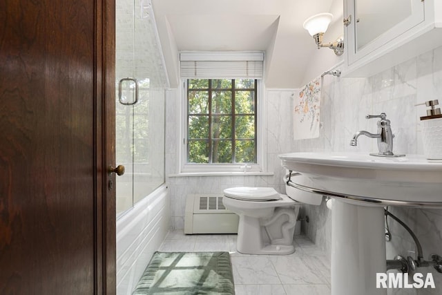 bathroom with marble finish floor, shower / bath combination with glass door, toilet, and tile walls