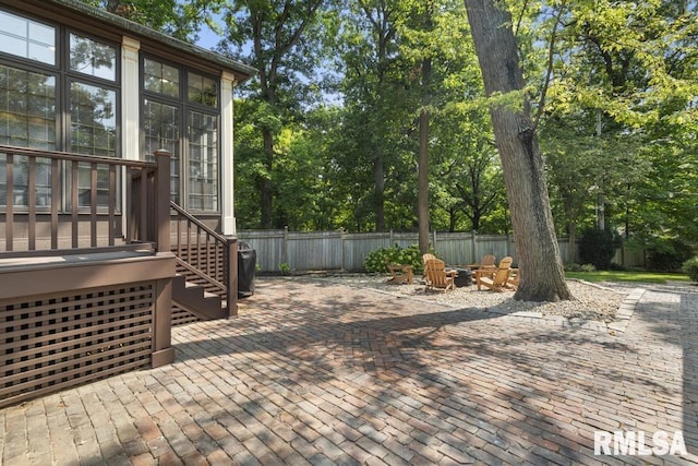 deck with an outdoor fire pit, fence, and a patio