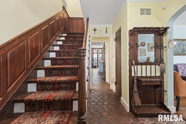 staircase with visible vents and crown molding