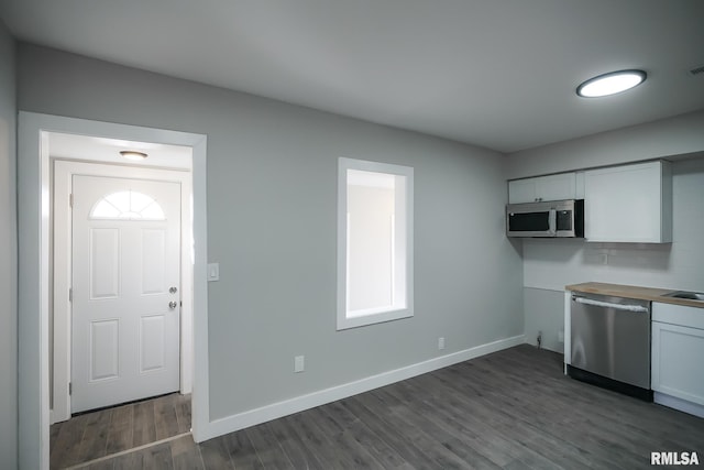 kitchen with appliances with stainless steel finishes, white cabinets, baseboards, and dark wood-style floors