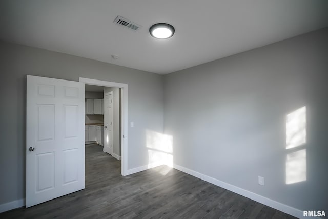 unfurnished bedroom with dark wood-style flooring, visible vents, and baseboards