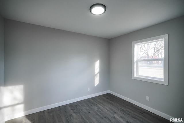 spare room with baseboards and dark wood finished floors