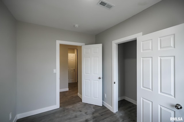 unfurnished bedroom featuring visible vents, dark wood finished floors, and baseboards