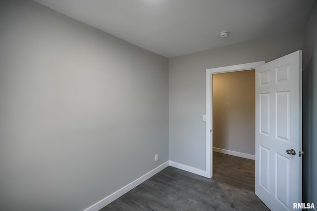 spare room with dark wood-type flooring and baseboards