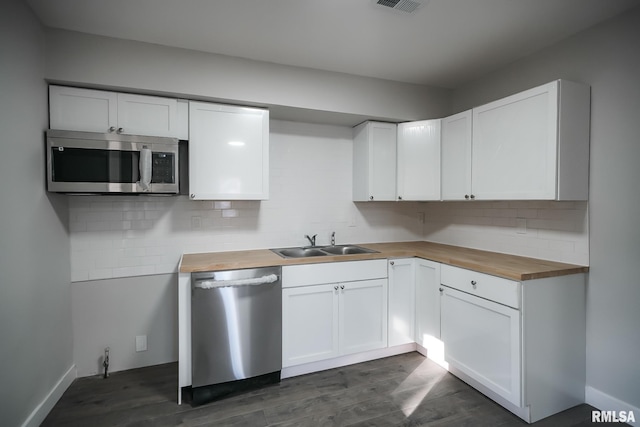 kitchen featuring tasteful backsplash, appliances with stainless steel finishes, white cabinets, a sink, and wood counters