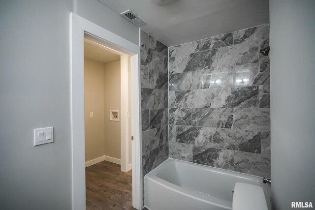 full bath featuring visible vents, bathing tub / shower combination, baseboards, and wood finished floors