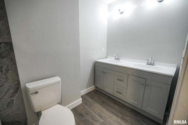 full bathroom with double vanity, wood finished floors, a sink, and toilet