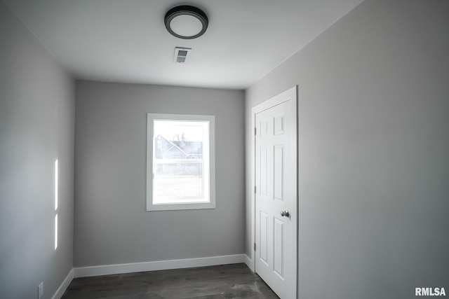 unfurnished room with dark wood-type flooring, visible vents, and baseboards