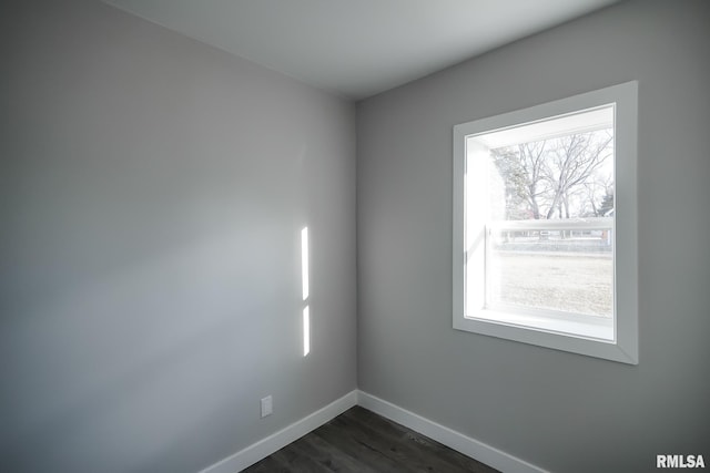 spare room featuring dark wood-style flooring and baseboards