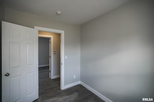 empty room featuring dark wood-style flooring and baseboards