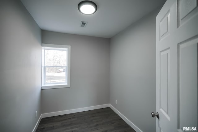 spare room featuring dark wood-style floors and baseboards